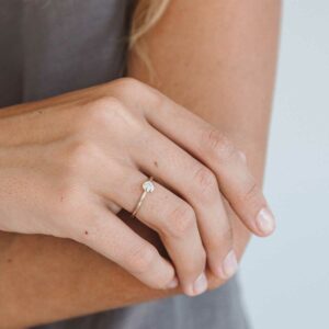 mão feminina usando anel de noivado minimalista de ouro 18k com diamante de 30p feito à mão