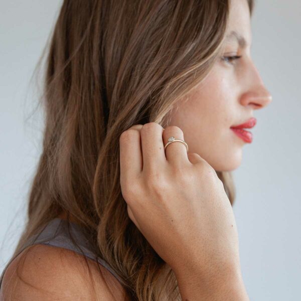 mulher usando anel de noivado minimalista de ouro 18k com diamante de 30p feito à mão