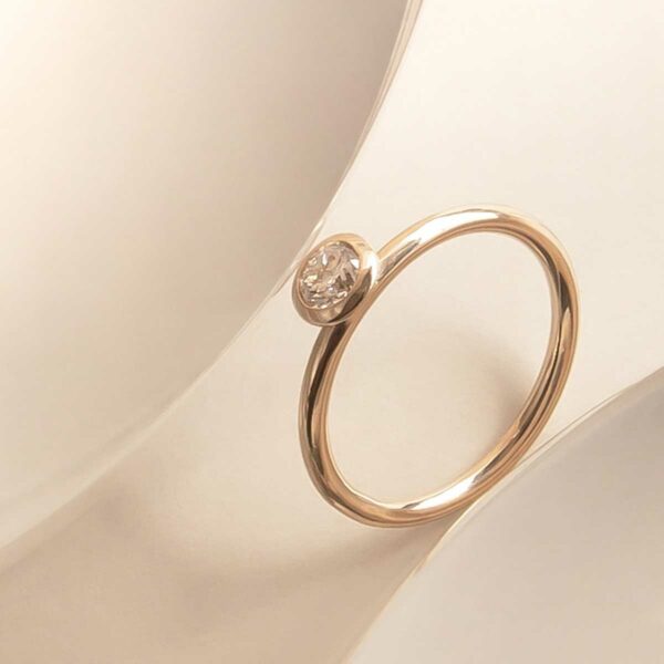 anel de noivado minimalista de ouro 18k com diamante de 30p feito à mão sobre mesa branca