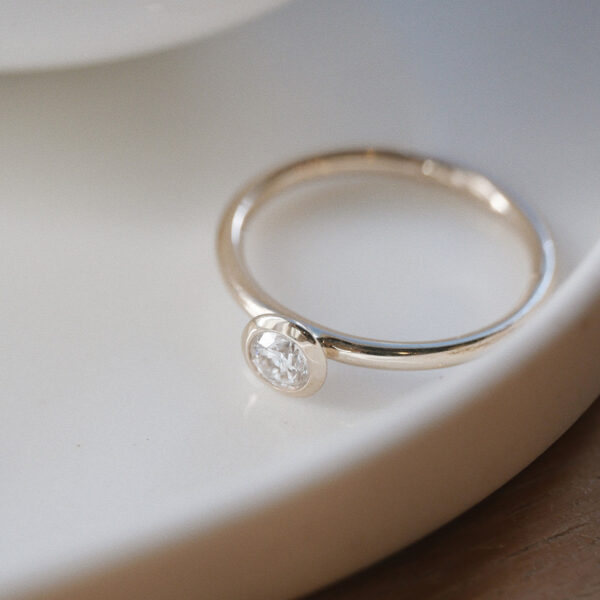 anel de noivado minimalista de ouro 18k com diamante de 30p feito à mão sobre prato de cerâmica