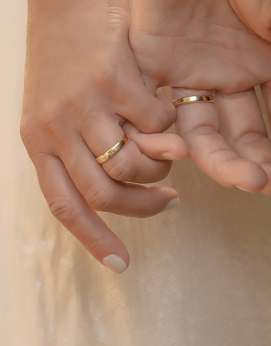 Uma mão masculina, e uma mão feminina vestindo aliança nordic de ouro 18k