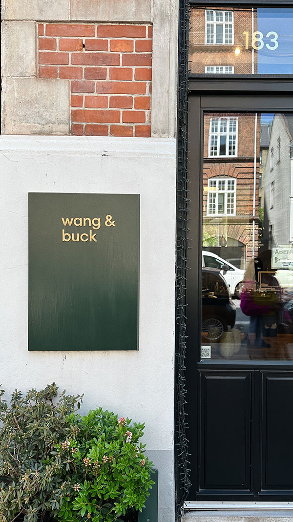 faixada da galeria wang em copenhagen com letreiro verde e dourado