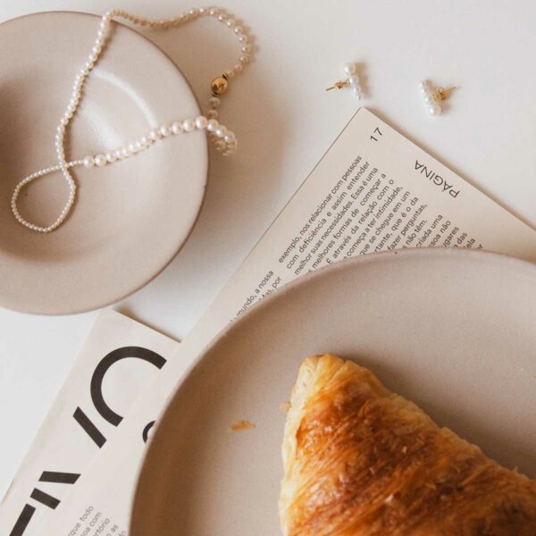 fotografia flatlay joias de pérolas, croissant e café