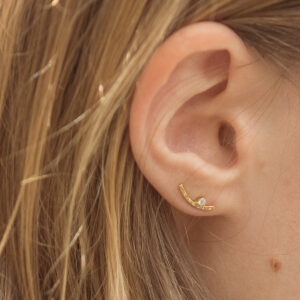 Mulher usando Brinco minimalista com diamantes feito a mão em ouro 18k martelado usado como ear cuff