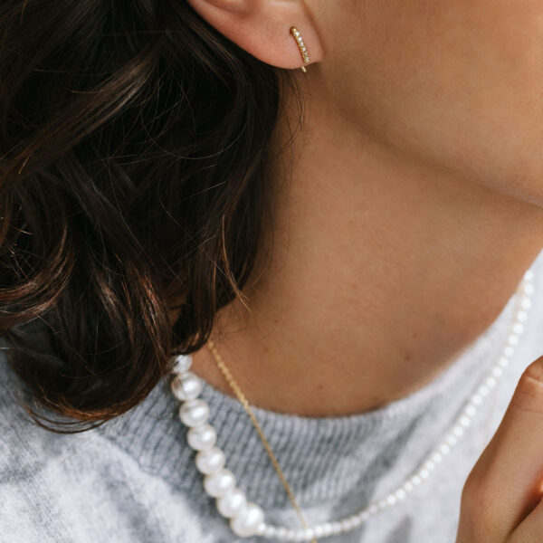 Mulher usando colar de pérolas e Brinco delicado minimalista cravejado feito a mão em ouro 18k com formato de figo