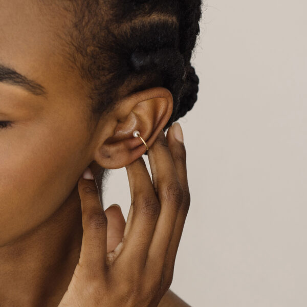 Mulher usando Ear cuff minimalista usada como piercing feita a mão em ouro 18k com pérola natural