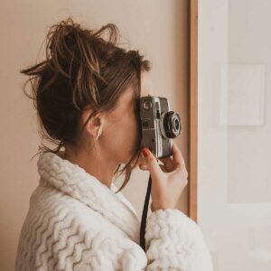 Mulher tirando foto com câmera usando Brinco minimalista feito a mão em ouro 18k com sete pérolas naturais em tamanhos diferentes