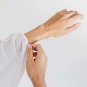Mulher usando Duas Pulseiras minimalistas representando filha feitas a mão em ouro 18k com diamante e corrente cartier fina