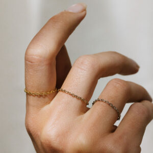 Mulher usando Anéis minimalistas feitos a mão com correntes em diferentes tons de ouro 18k